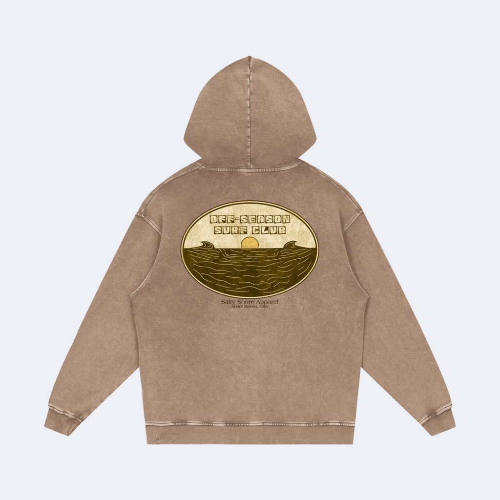 A brown acid-wash hoodie shown from the back, featuring a large circular graphic print with a sunset and ocean waves, and the text 'OFF THE BEACH OFF THE COAST'.