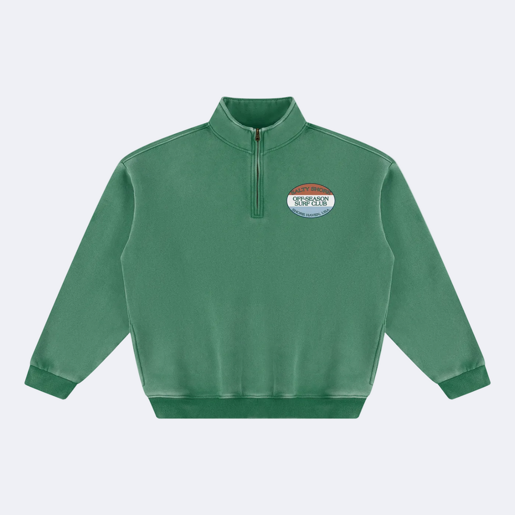 A green long-sleeve quarter-zip sweatshirt with a mock neck collar and a small oval chest graphic, displayed on a solid white background.