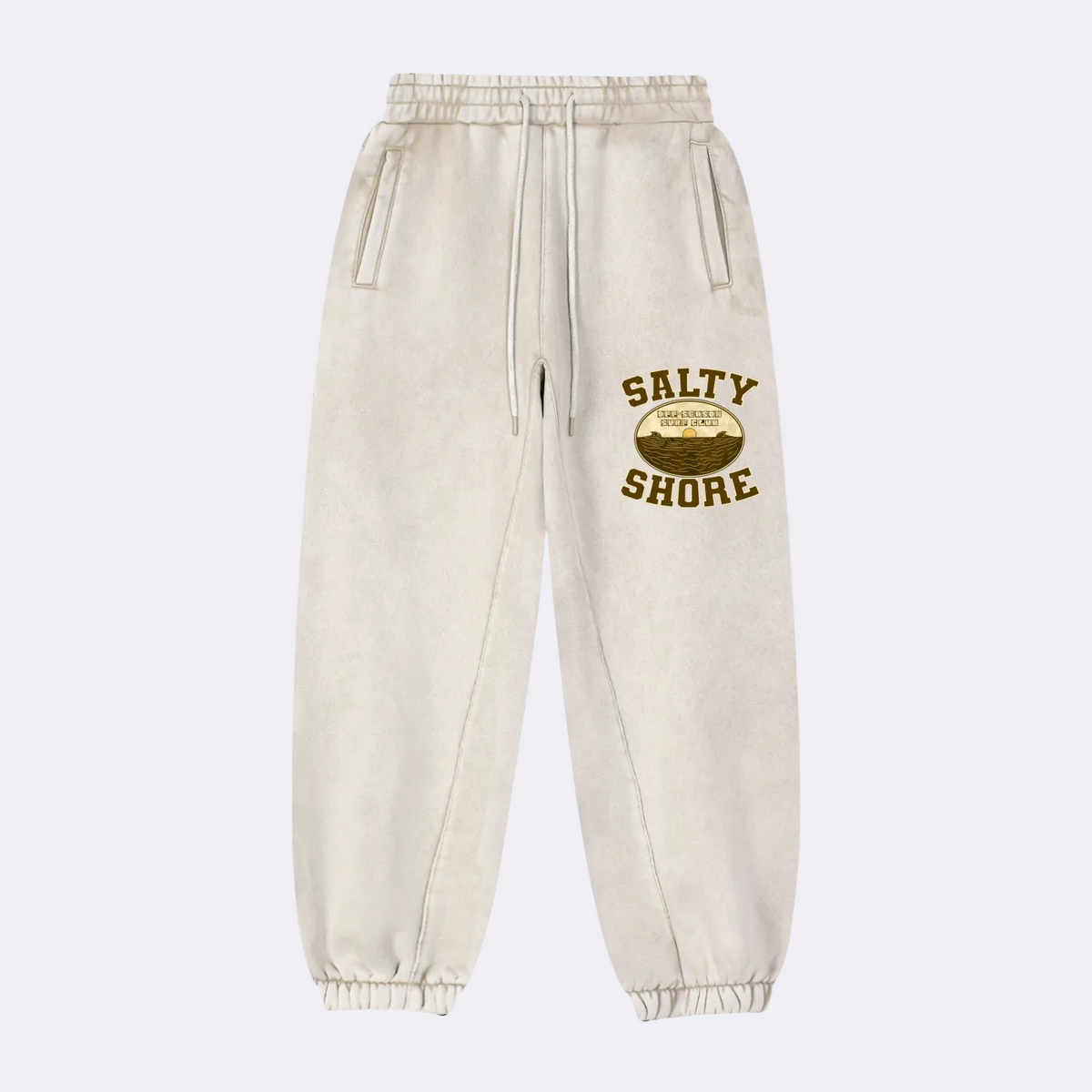 Off-white washed sweatpants with a brown and gold 'SALTY SHORE' graphic on the left thigh, featuring an elastic waistband with drawstrings and elastic cuffs.